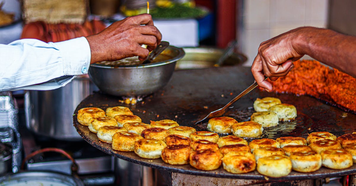 Close-up of a street vendor preparing traditional fried snacks on an outdoor grill.