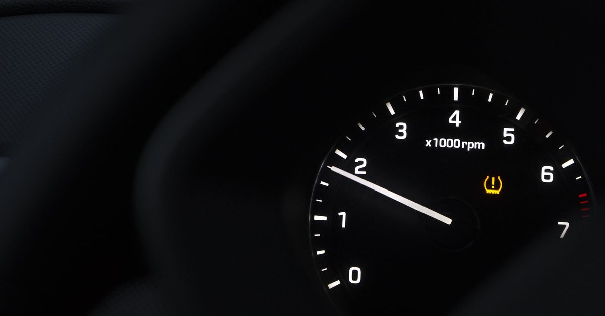 A detailed view of a car tachometer showing RPM with tire pressure warning.