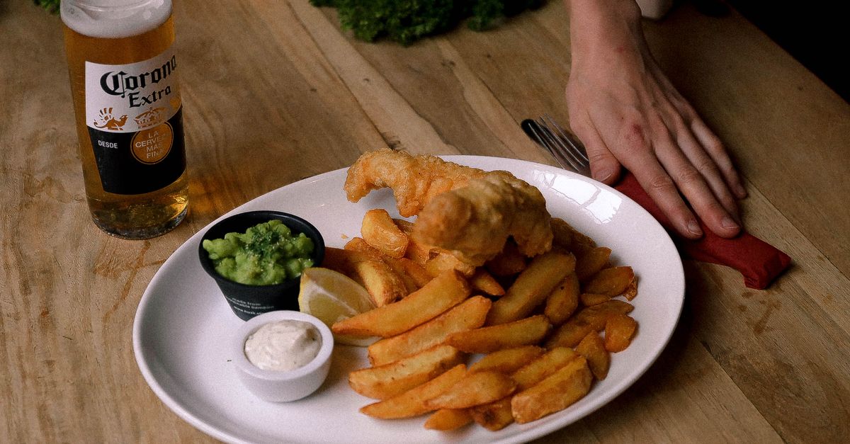 Delicious fish and chips with cold beer served on a wooden table, perfect for a casual meal.