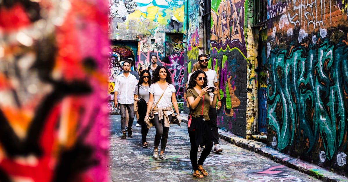 Tourists explore Melbourne's vibrant graffiti-covered alley, capturing urban artistry in a colorful scene.