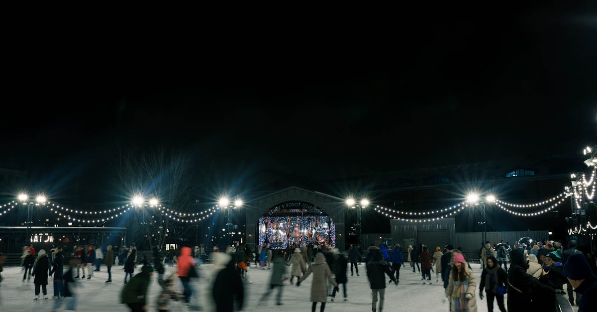People enjoy ice skating under lights on a winter night.
