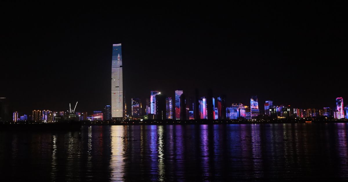 Beautiful city skyline at night with colorful lights reflecting in a calm harbor.