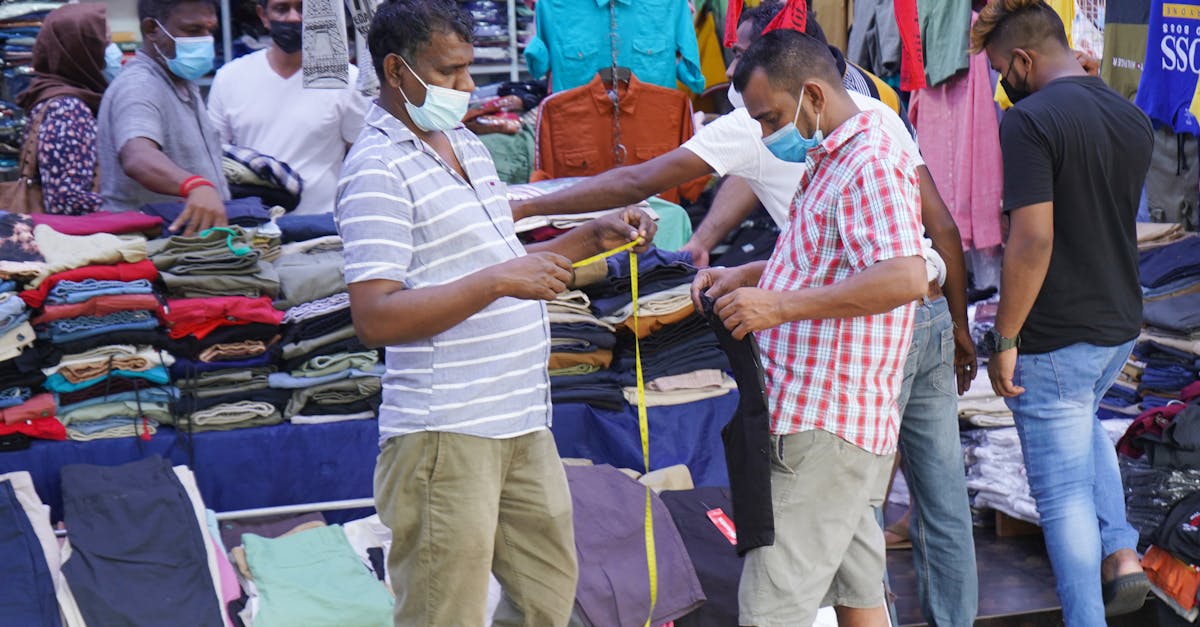 Customers shopping for clothes at a street market, all wearing masks.