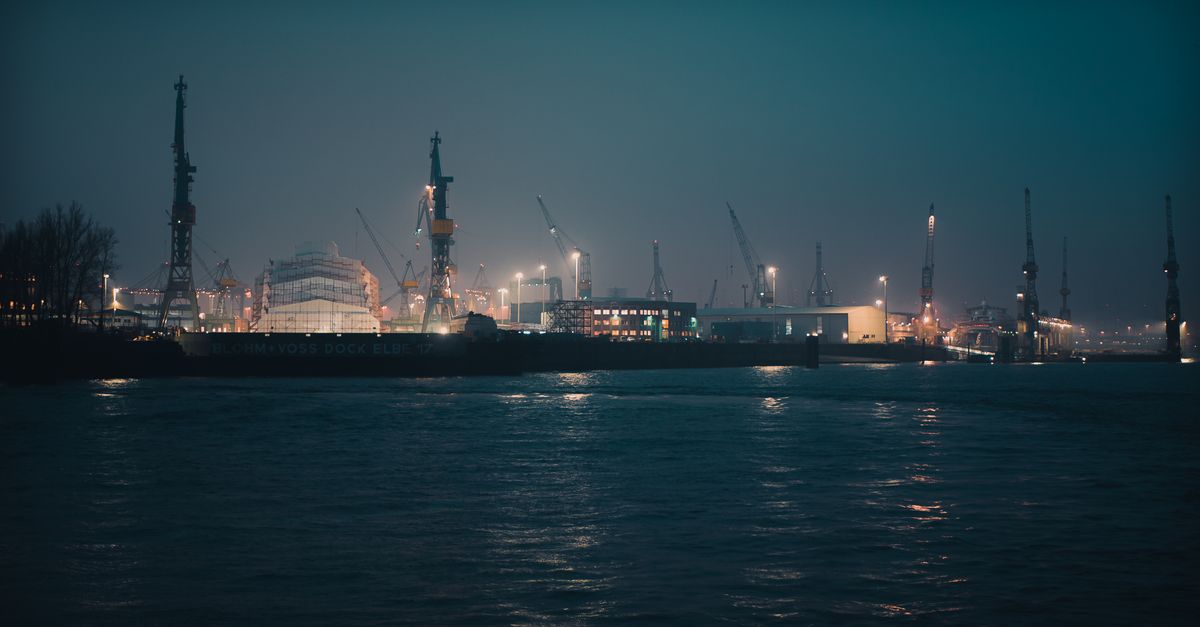 Scenic night view of a bustling and illuminated container port with harbor cranes.