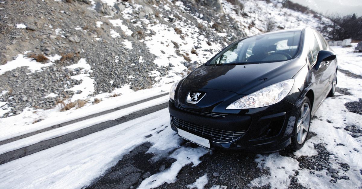A black car navigates a snowy mountain road, showcasing winter travel and adventure.