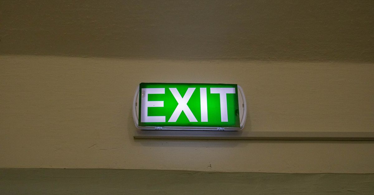 Bright green exit sign mounted on a hallway wall, offering clear direction for emergency evacuation.