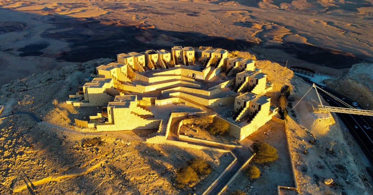 A breathtaking aerial view of Mitzpe Ramon Crater in Israel's Negev Desert, showcasing stunning stone buildings at sunset.