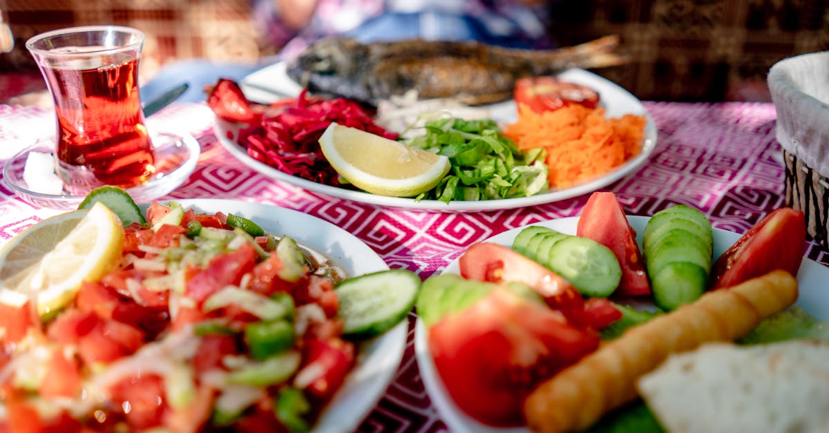 Close-up of a Mediterranean meal with grilled fish, fresh salad, and tea on a restaurant table.