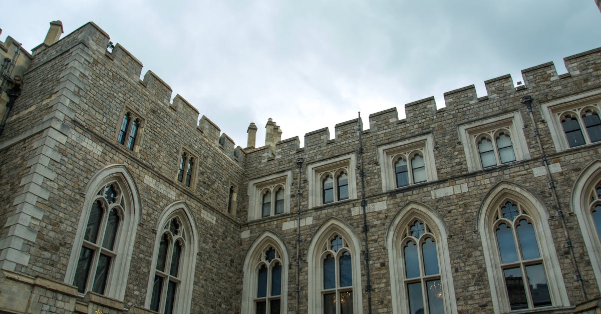 Low-angle view of a historic castle with Gothic architecture and a cloudy sky background.