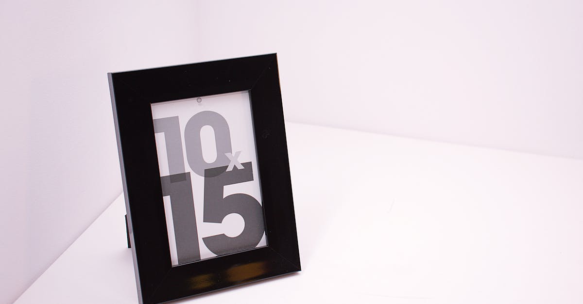 A stylish black photo frame standing on a white surface with minimalist design.