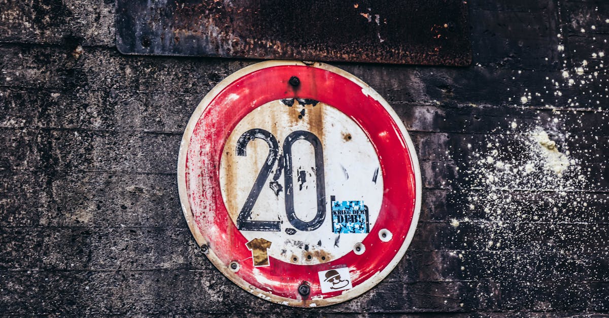 Close-up of an old rusty speed limit sign with '20' featuring on a textured concrete wall.