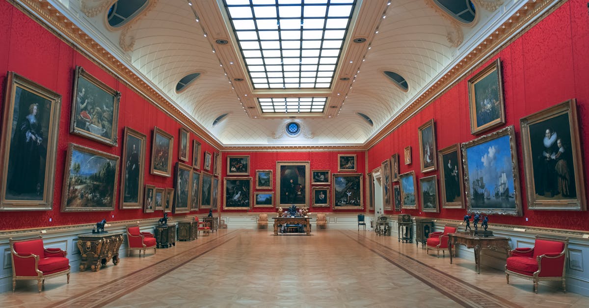 Elegant art gallery in London displaying classic paintings on red walls under skylit ceiling.