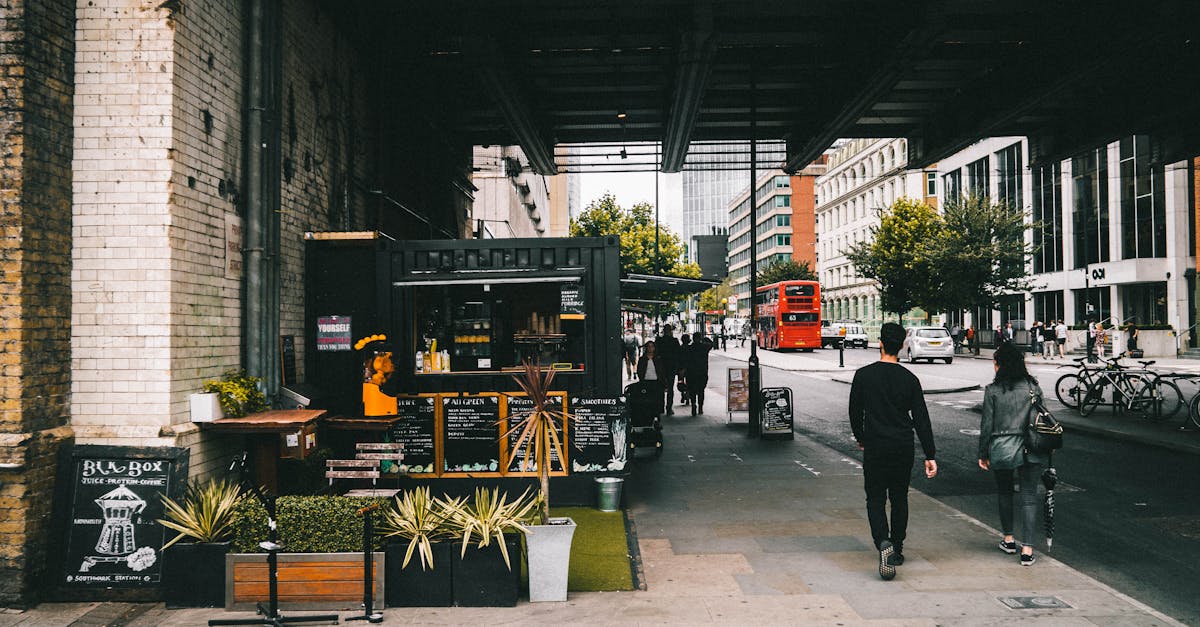 A vibrant street market scene under a bridge in London featuring a coffee booth and pedestrians.