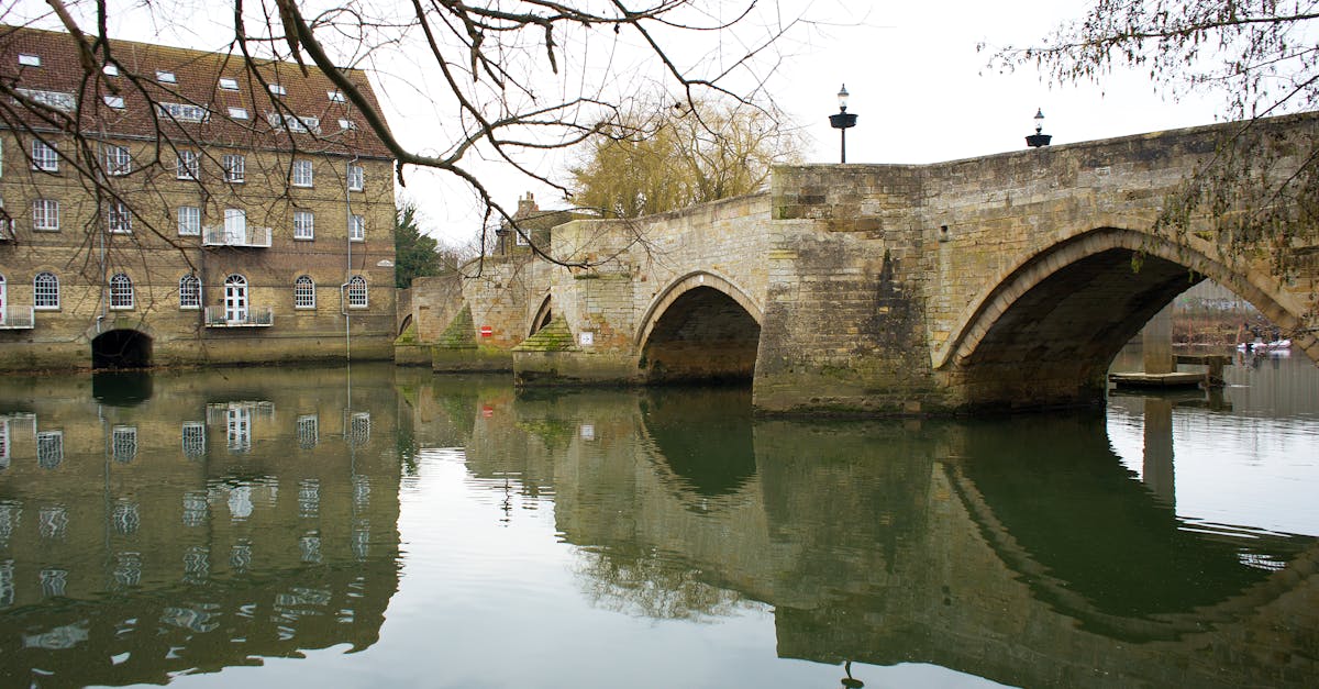 A picturesque stone bridge over a tranquil river in Godmanchester, showcasing historic architecture.