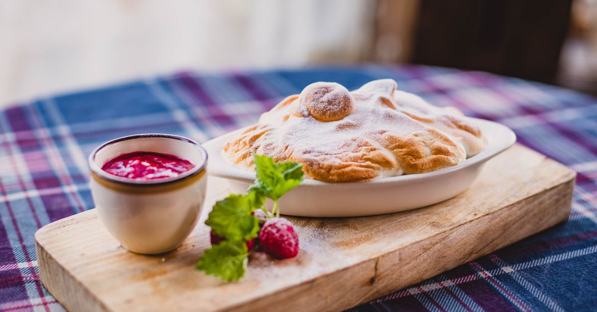 Delicious baked dessert with berry sauce and mint on wooden board.