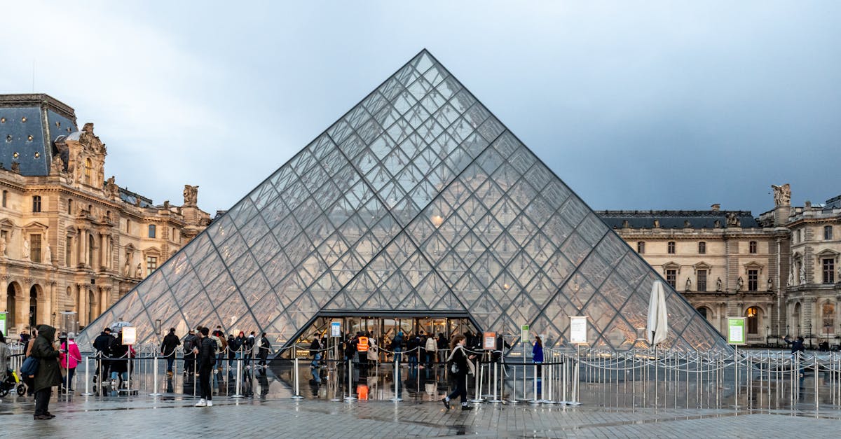 Visitors at the Louvre Pyramid entrance in Paris showcasing modern architecture.