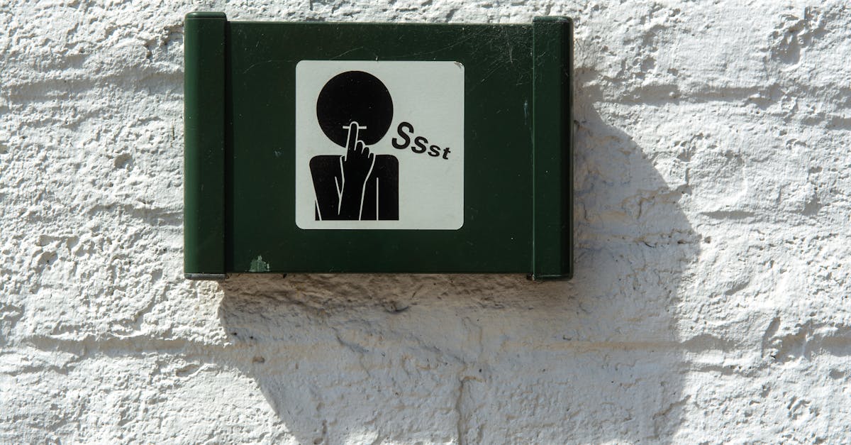 A green sign on a white brick wall indicating silence with a 'Ssst' symbol.