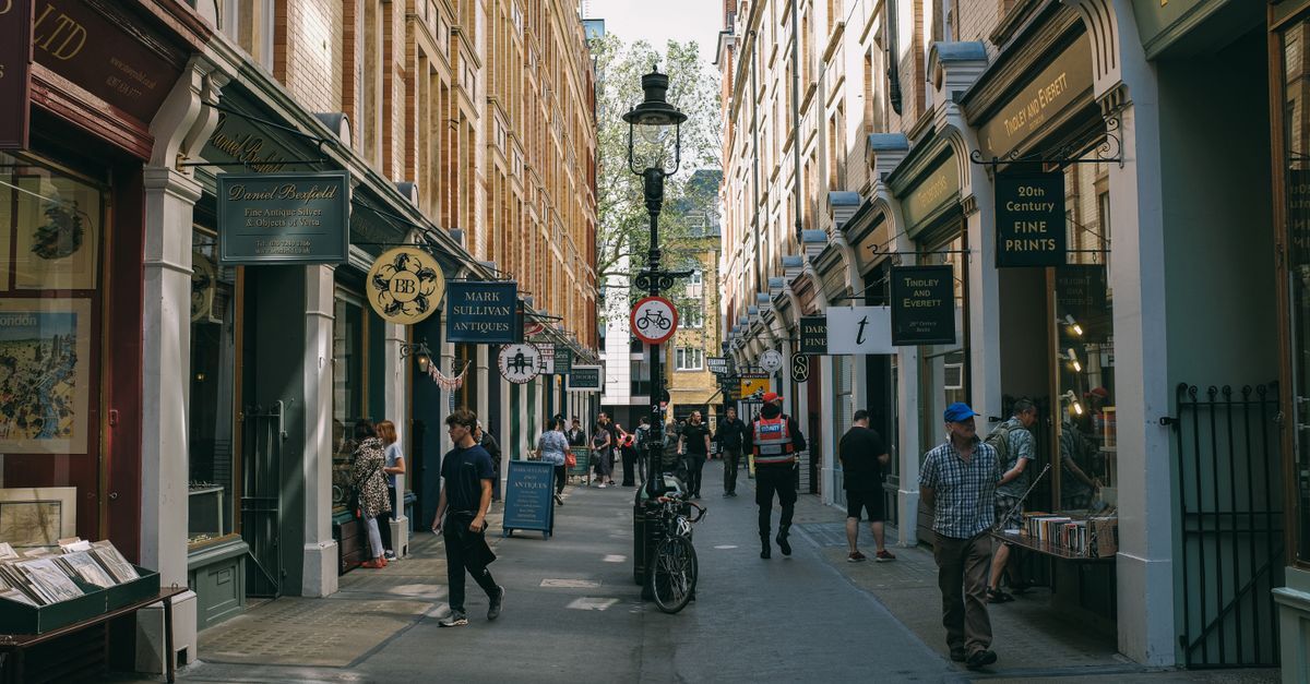 Lively London street scene with people shopping in a narrow alley filled with antique shops.