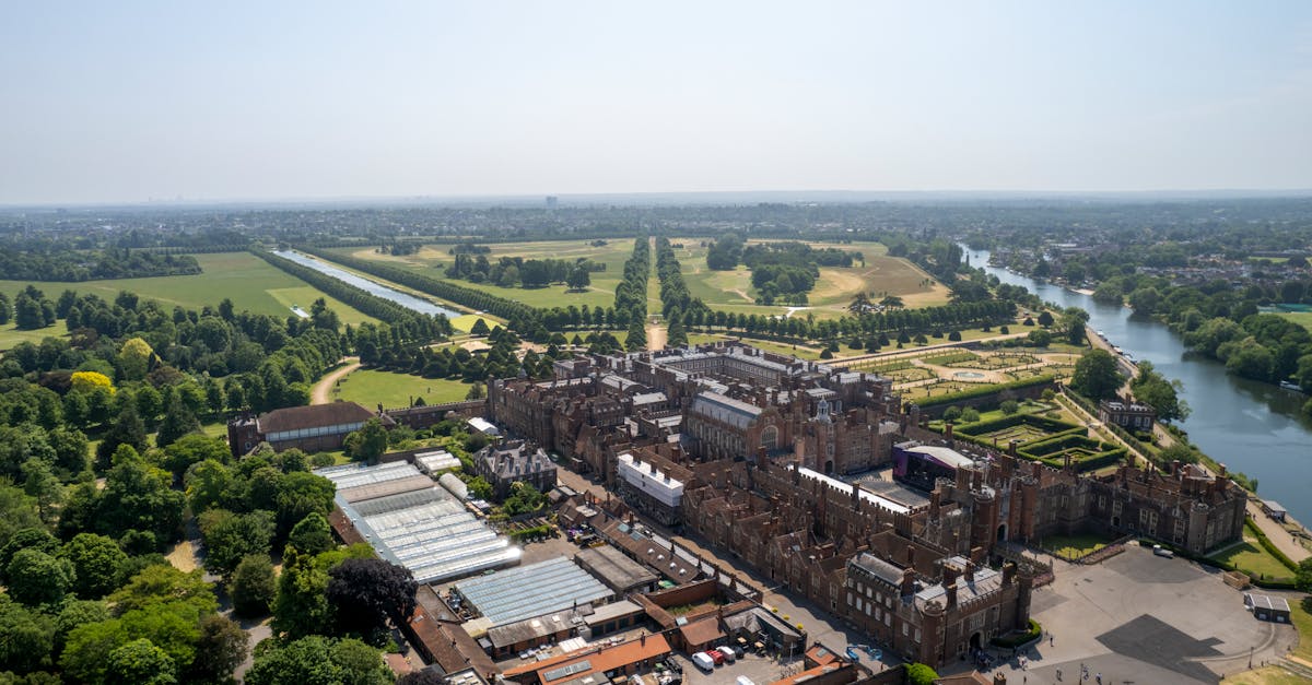 Stunning aerial view of Hampton Court Palace surrounded by lush gardens and the River Thames.