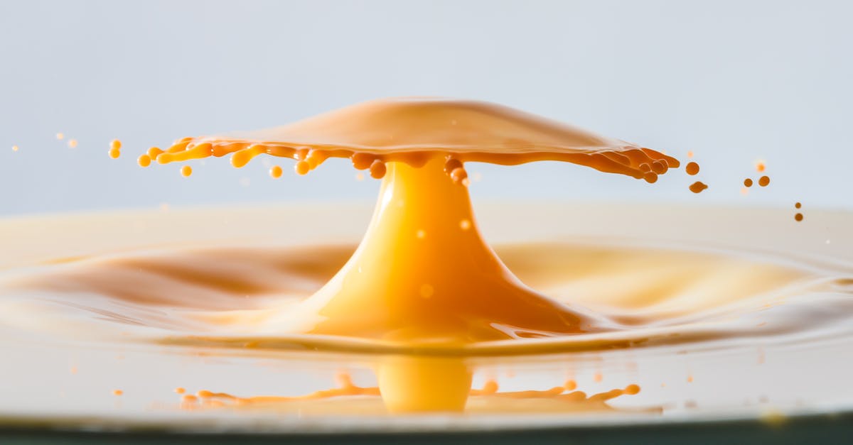 Macro photography of an orange liquid splash resembling an umbrella formation, captured in high speed.