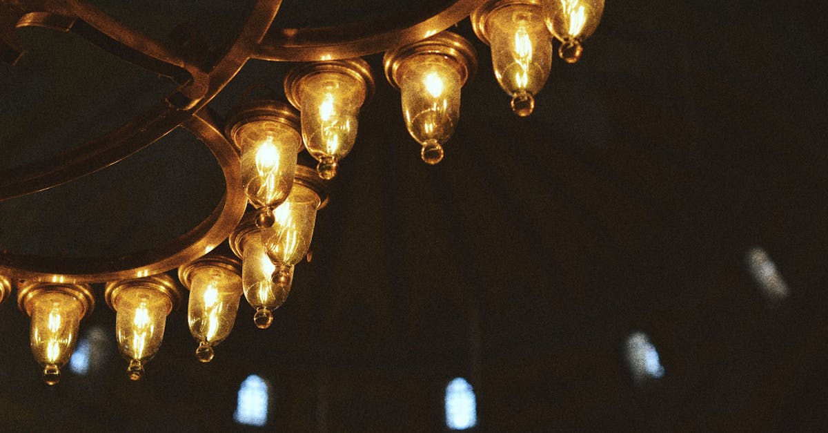 Close-up of a luxurious bronze chandelier with glowing bulbs in an ornate interior.