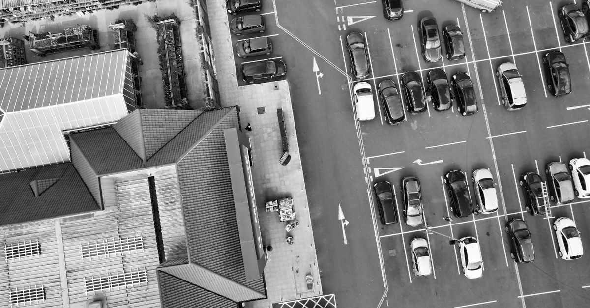 Black and white aerial view of a parking lot and buildings in England, showcasing urban life and architecture.