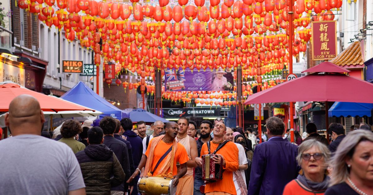 Musicians and crowds celebrate under lanterns in London's iconic Chinatown.