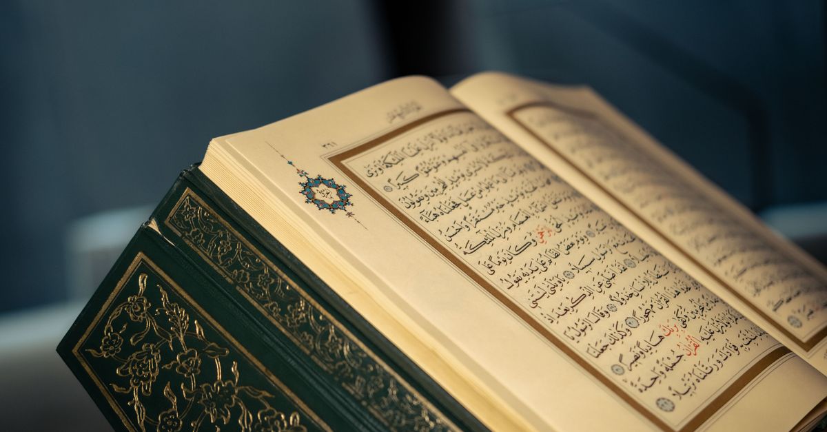 Close-up of an open Quran displaying intricate Arabic calligraphy on a page.