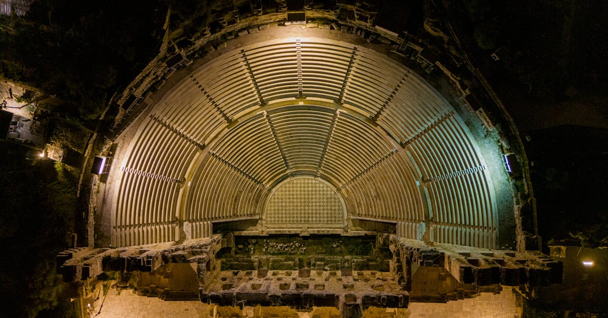 Stunning aerial view of an ancient amphitheater in Athens, illuminated at night showcasing historical architecture.