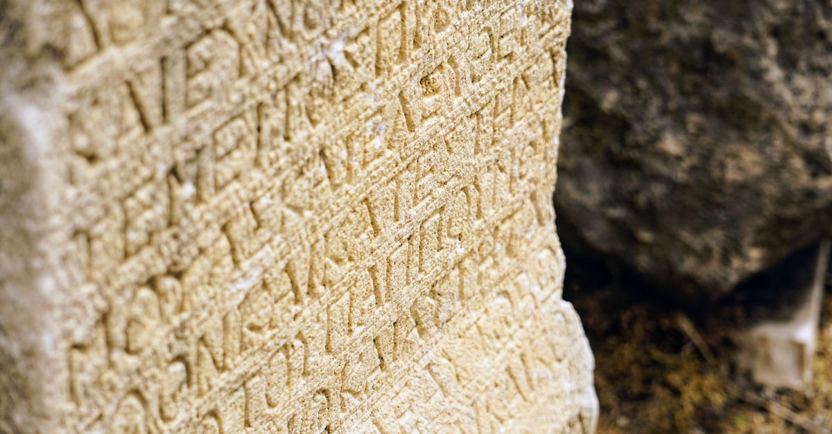 Close-up view of an ancient stone tablet with intricate engraved text, capturing historical artistry.