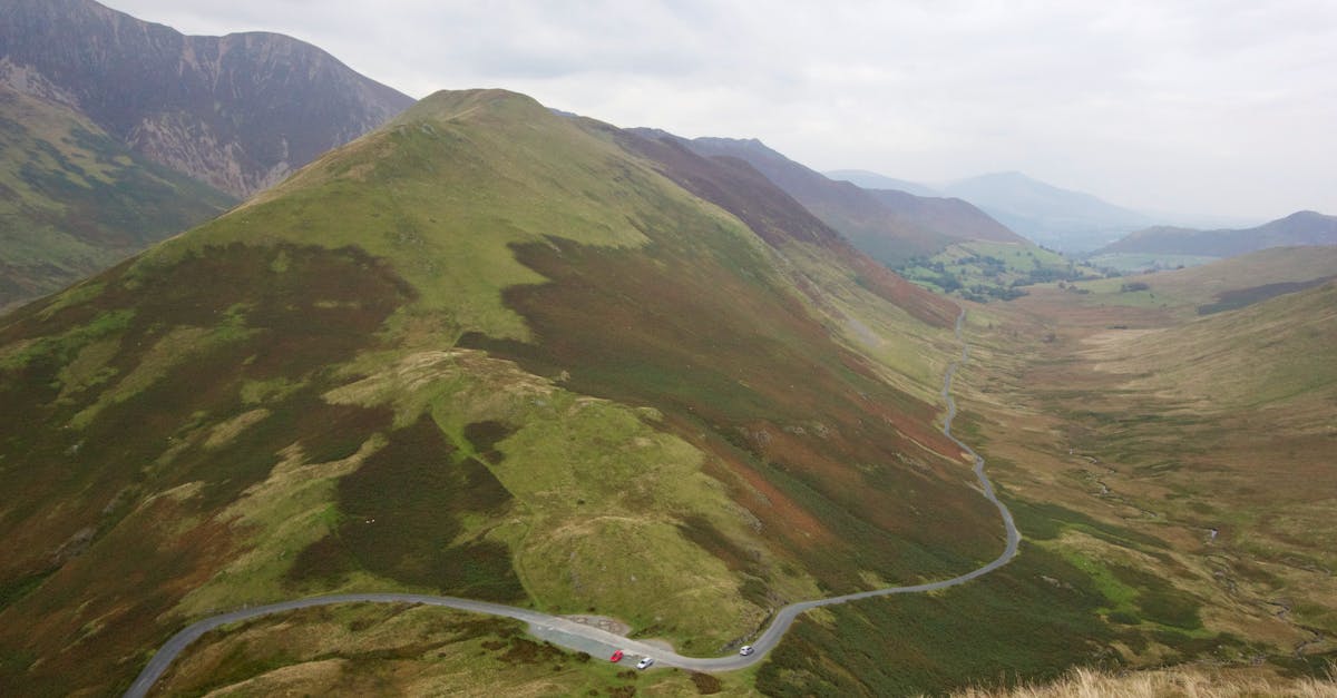A stunning view of lush green mountains with a winding road under an overcast sky.