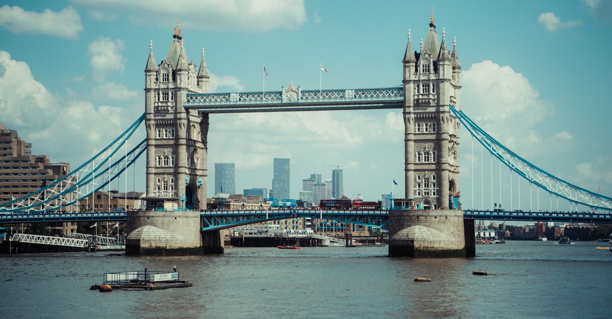 Iconic Tower Bridge in London stands tall over the River Thames under a bright blue sky.