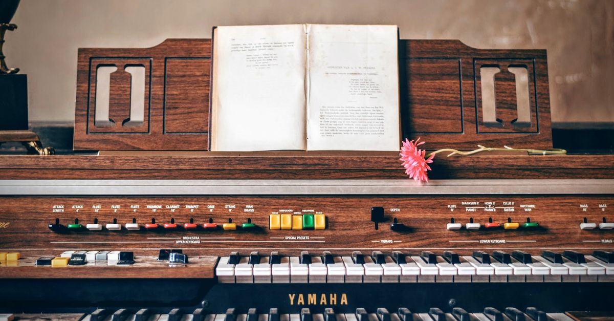 Close-up of a vintage Yamaha organ with sheet music and a pink flower, perfect for musical nostalgia.