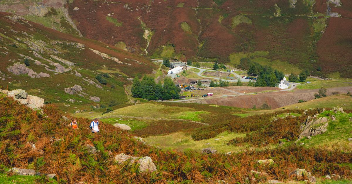 Beautiful rural landscape showcasing hikers in a lush valley surrounded by mountains and nature.