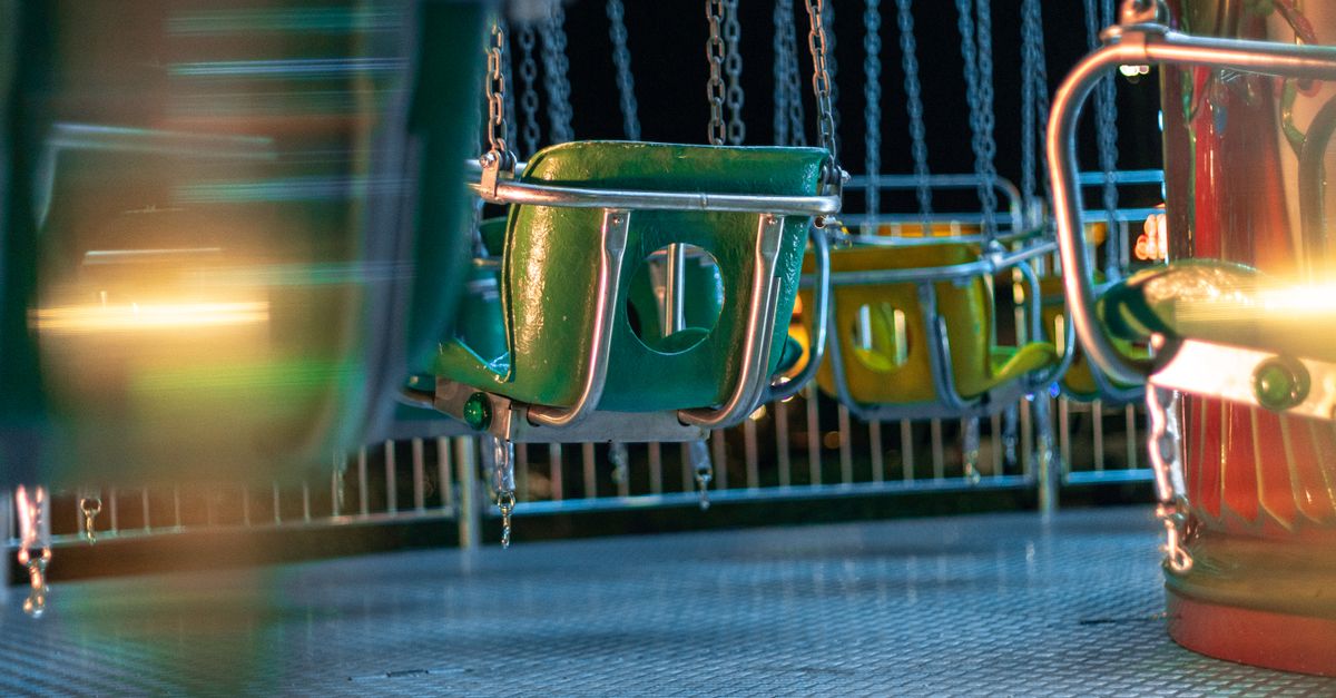 Vividly colored, empty carousel seats at night in a gently blurred amusement park setting.