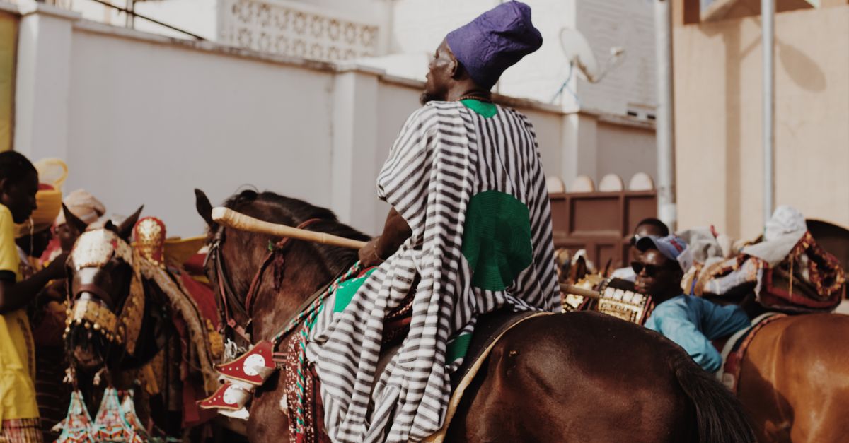 Colorful traditional horseback parade in urban street with riders in vibrant attire.