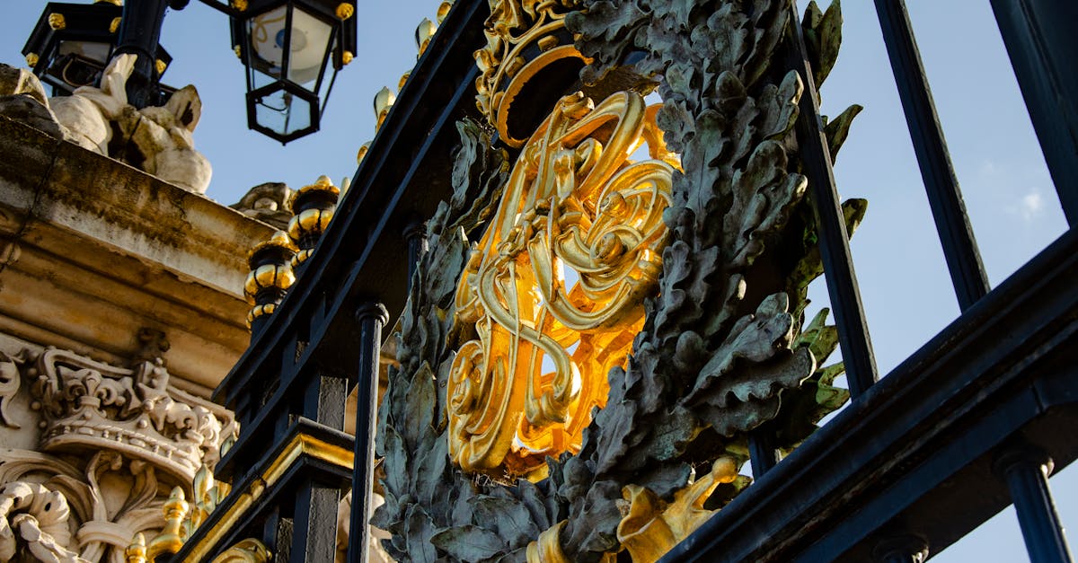 Close-up of gilded ironwork at Buckingham Palace gates in London, showcasing intricate design.