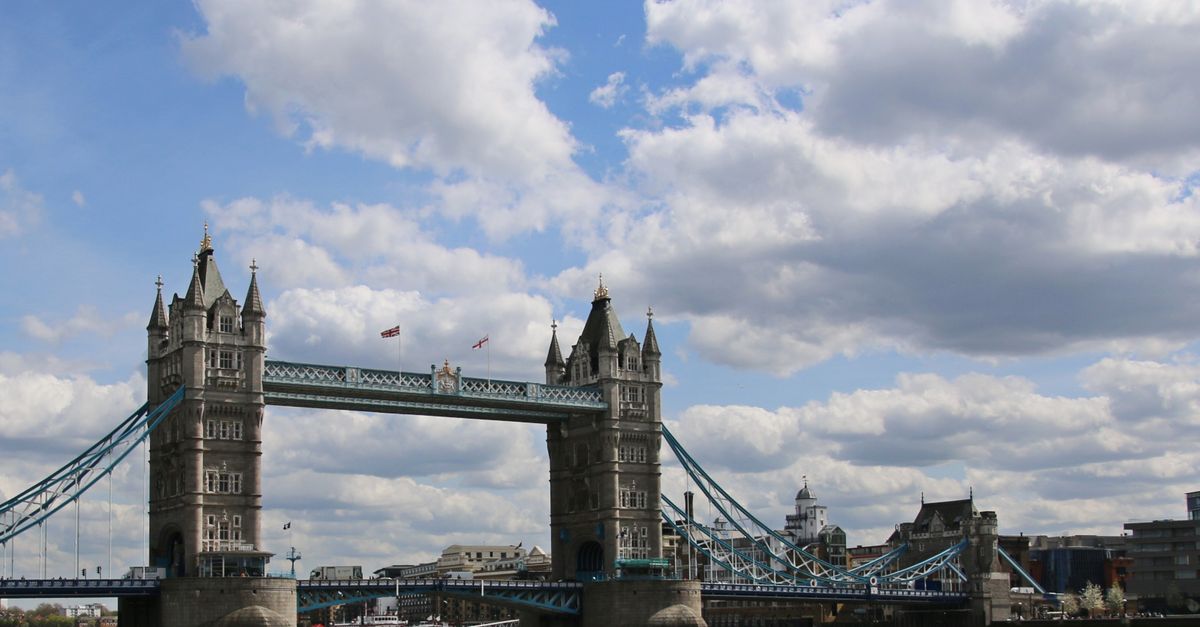 A stunning view of the Tower Bridge in London with fluffy clouds and a bright blue sky.