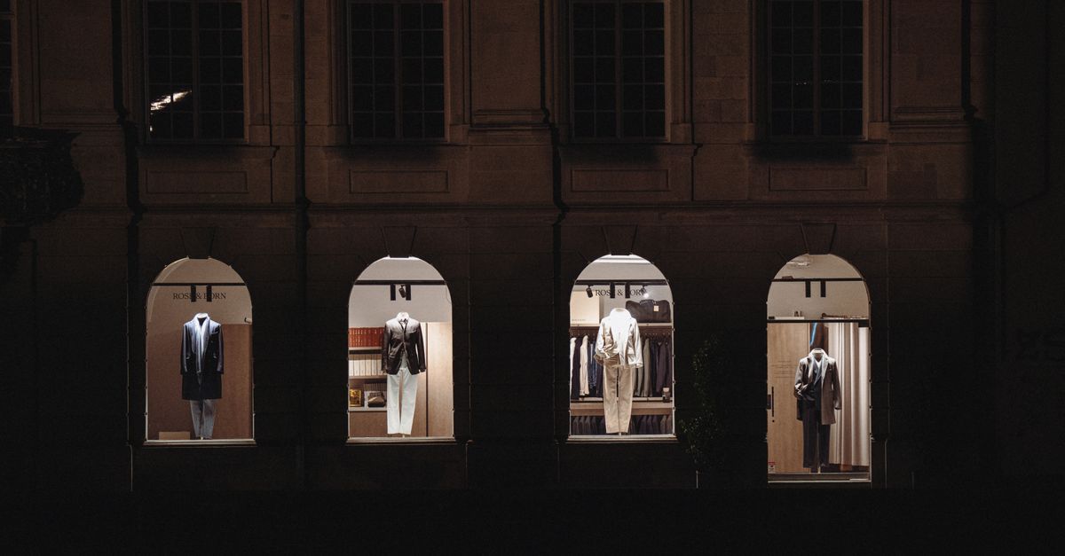Stylish clothing displays visible through urban building windows at night, highlighting luxury fashion.