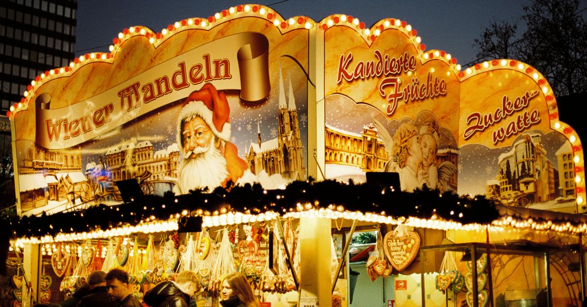 Illuminated Christmas market stall in Berlin showcasing traditional sweets and festive decor.