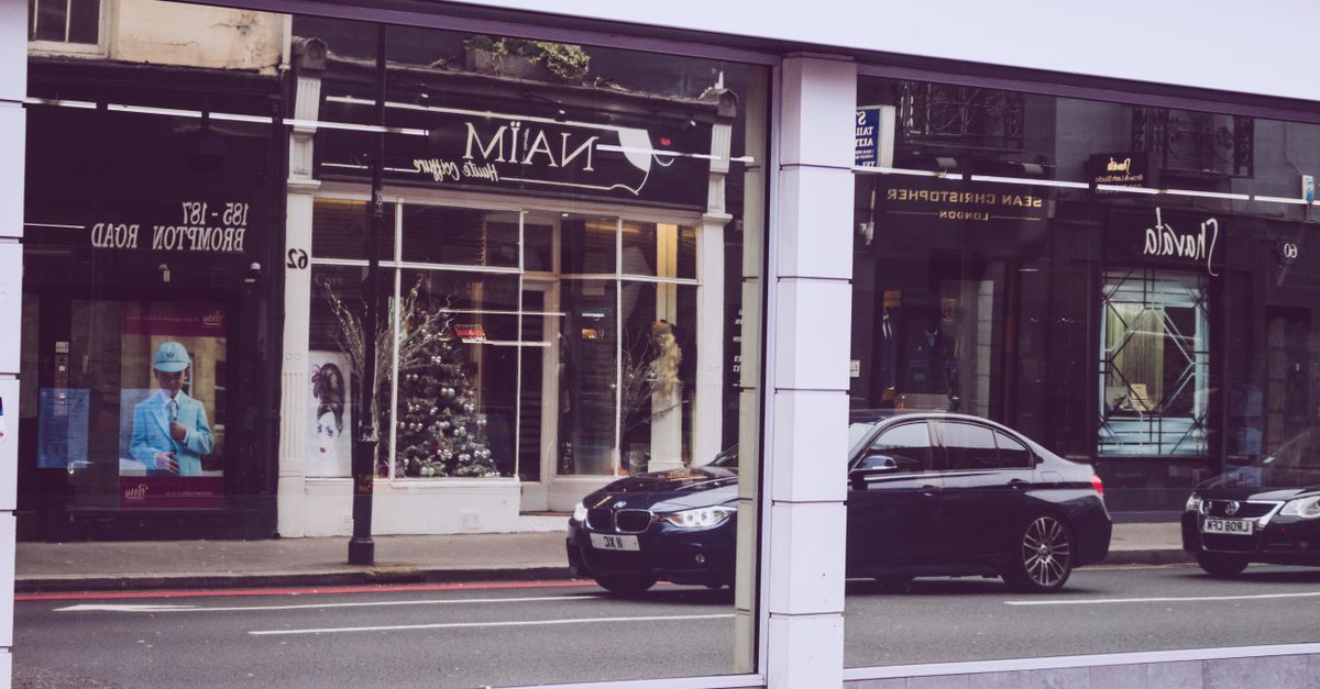 Street view in London with BMW car reflections and modern storefronts.