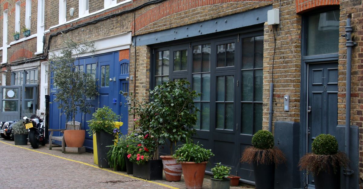 Picturesque London street with potted plants and brick buildings, showcasing urban charm.