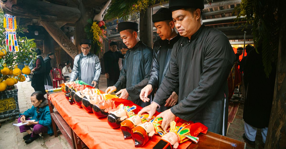 Men in traditional attire arranging puppets for a cultural ceremony