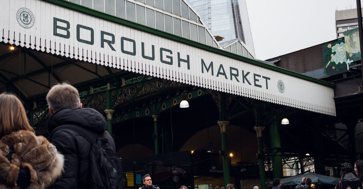 People enjoying a bustling day at London's iconic Borough Market with city skyscrapers in the background.