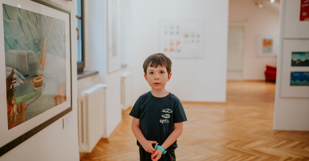 A young child stands in a bright art gallery, observing the paintings on display.