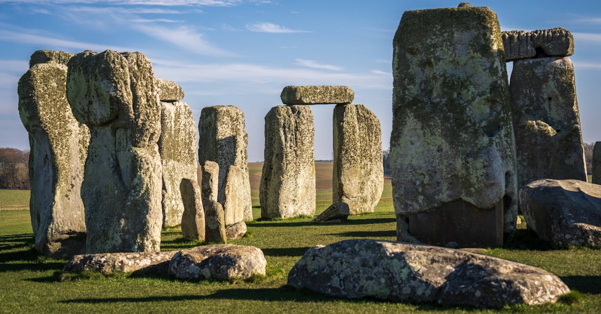Iconic view of Stonehenge under a clear blue sky, showcasing ancient stone formations on a sunny day.
