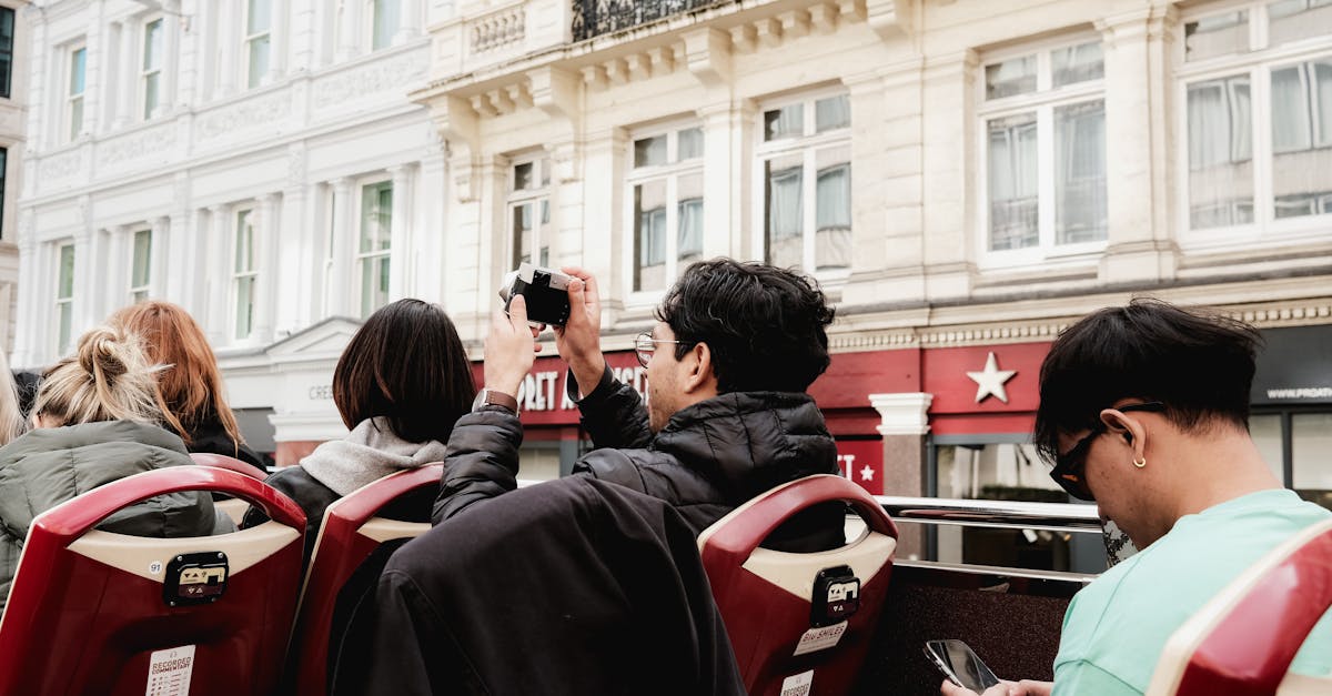 Back view of tourists on an open-top bus exploring city streets. Capturing memories.