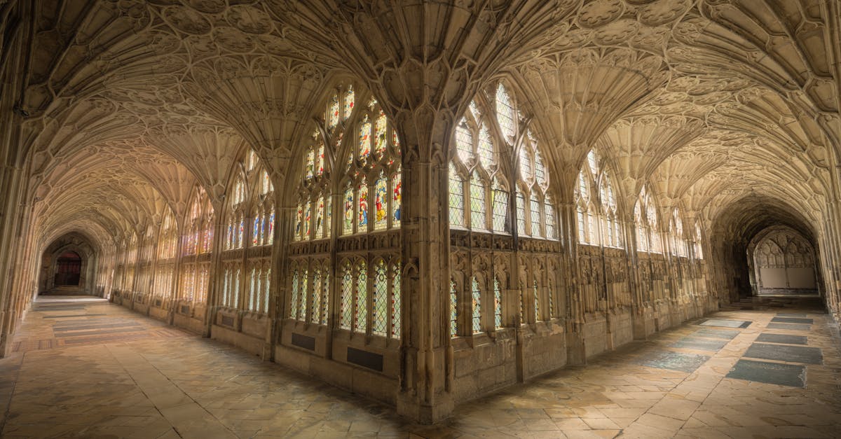 Intricate gothic cloisters with stained glass windows in Gloucester Cathedral, England.