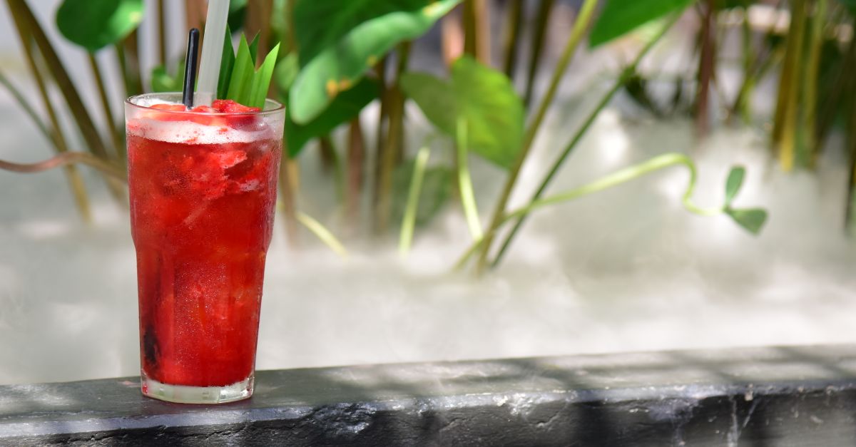 A vibrant iced berry drink with greenery in the background, perfect for summer refreshment.