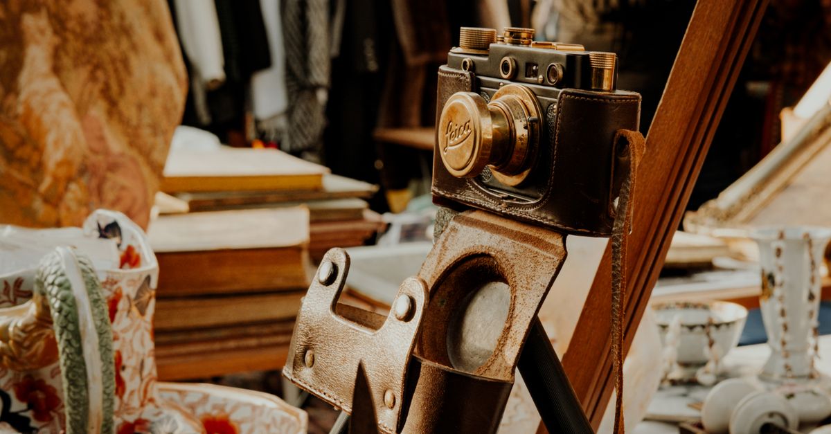 A classic vintage camera in a leather case displayed in an antique shop setting.